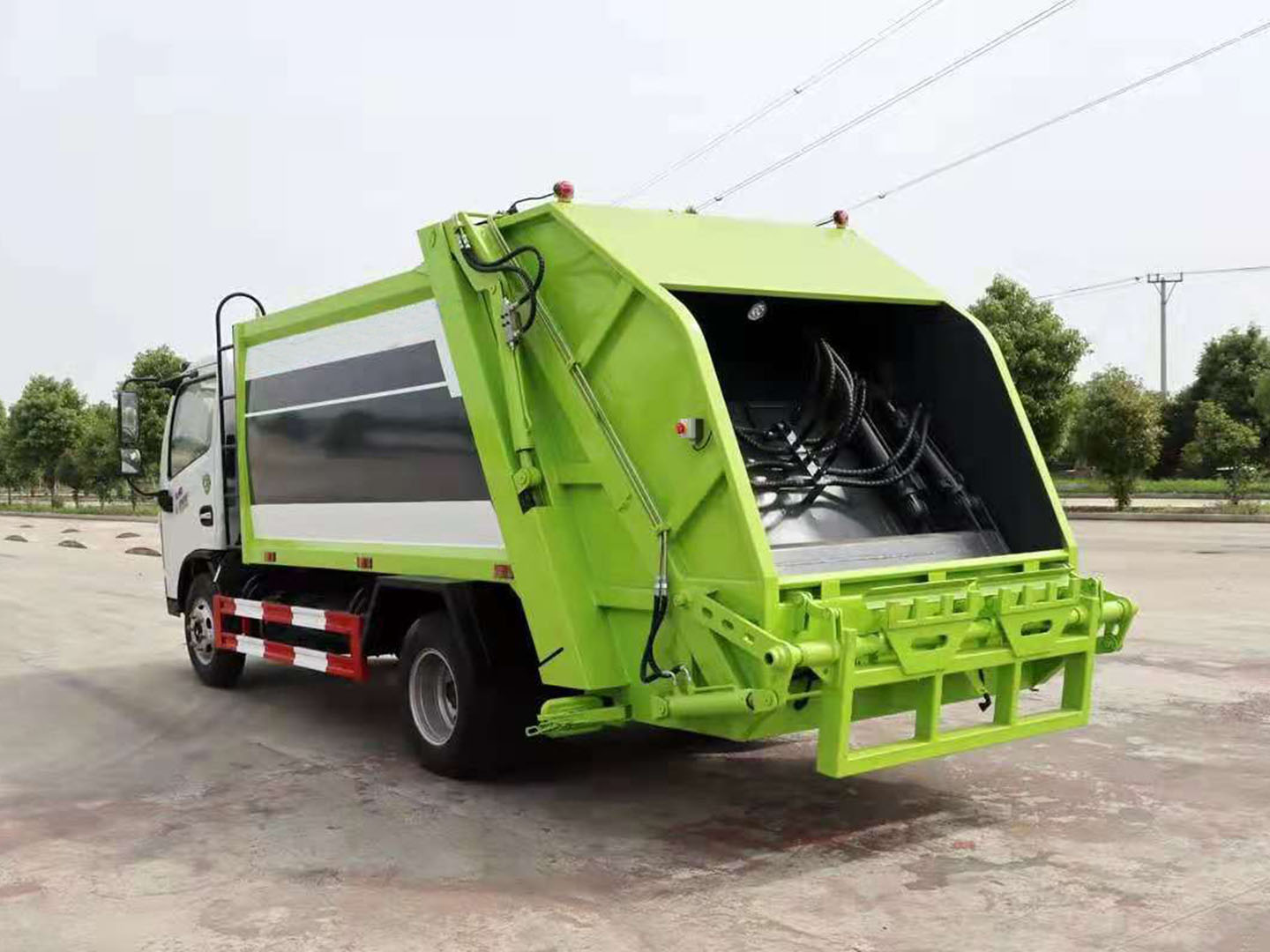 Rear view of waste compactor with hanging bucket mechanism